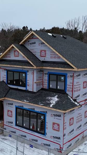 Aerial view of a new-build home mid-construction with a freshly shingled multi-gable roof