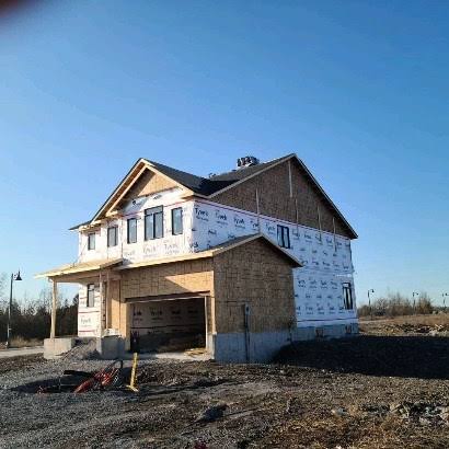 New-build home with roof trusses and porch framing under a clear sky