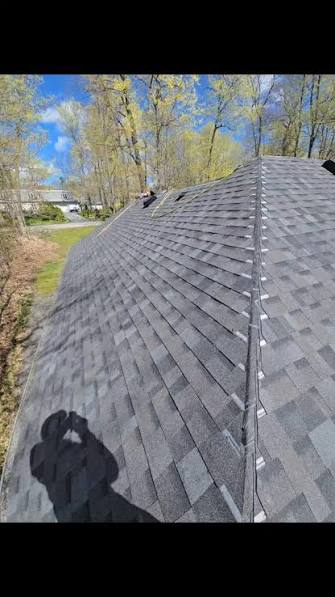 View looking down a freshly shingled roof plane toward the driveway below